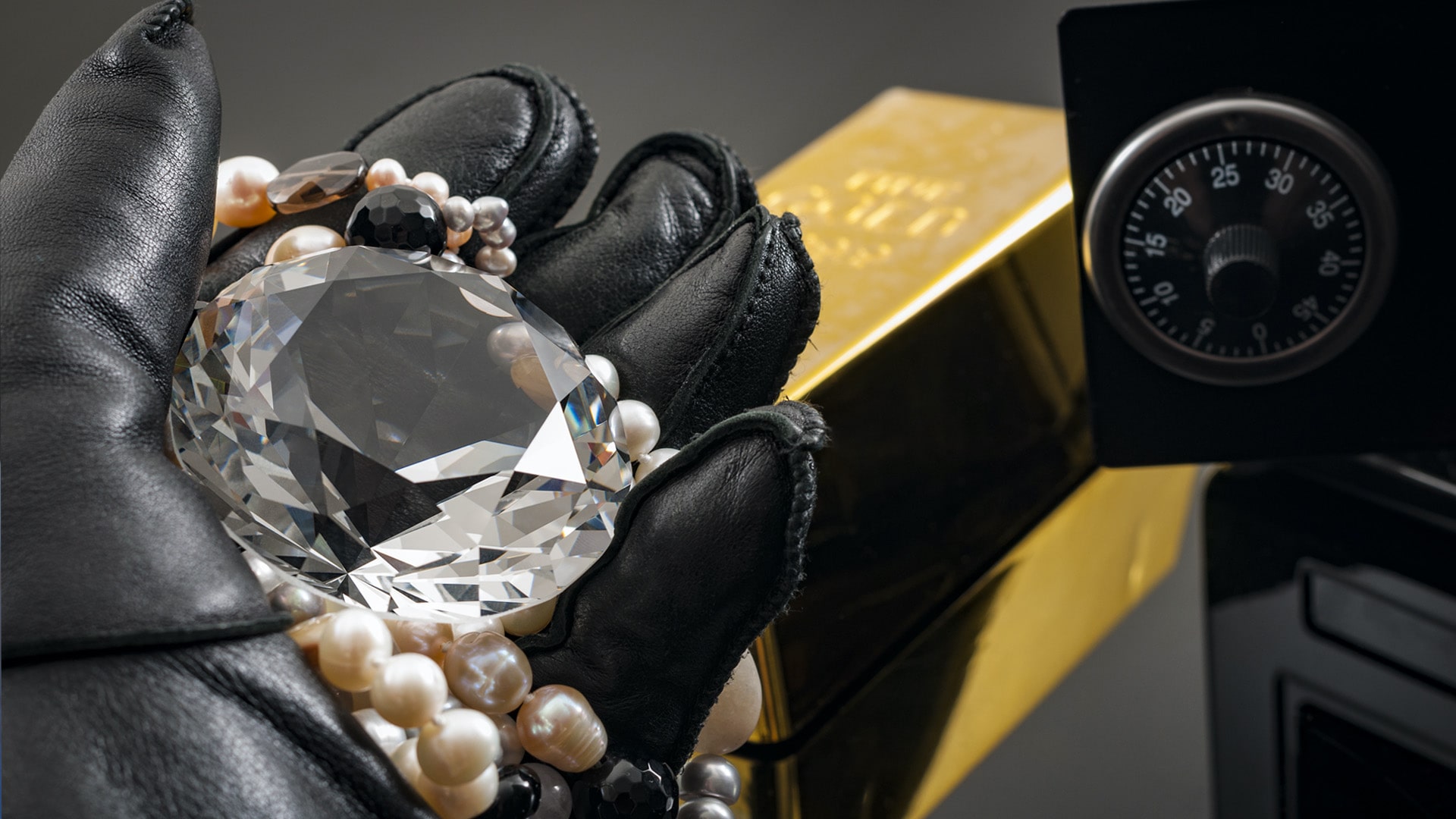 Home invasion and burglary concept with hand in leather gloves holding the loot a diamond and pearl necklace