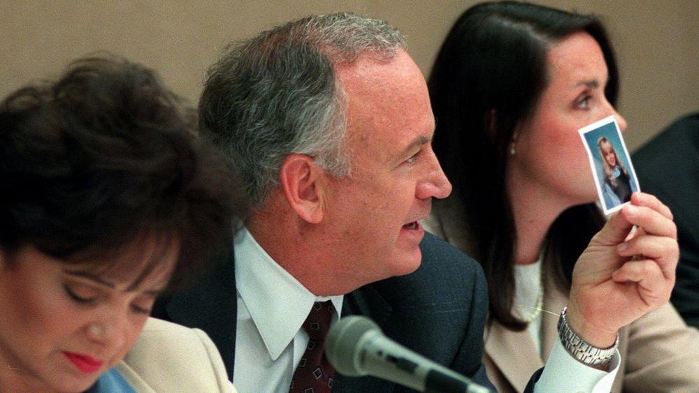 John Ramsey holds up a picture of his daughter, JonBenét, during a press conference