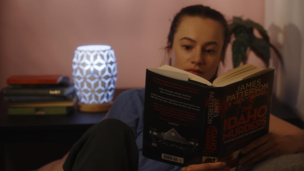A young woman reading 'The Idaho Murders' by James Patterson and Vicky Ward