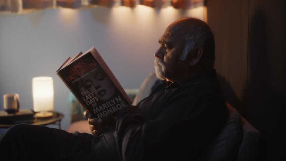 An older man reading 'The Last Days of Marilyn Monroe' by James Patterson