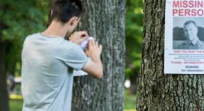 A young man puts up ads for a missing person in the park