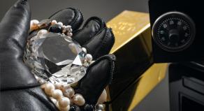 Home invasion and burglary concept with hand in leather gloves holding the loot a diamond and pearl necklace