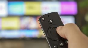 Male hand holding the TV remote control and changing TV channels