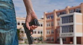 A man holding a gun outside of a high school