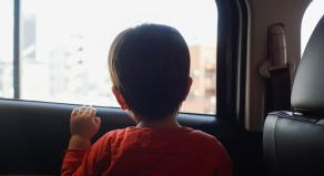 Little boy sitting in the car and look out from the car window.