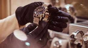 A pair of gloved hands examining expensive jewellery