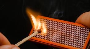 Man's fingers lighting a match