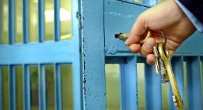 A prison guard using keys to lock a prison cell