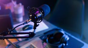A podcast microphone with headphones on the desk