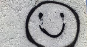 Black graffiti on a white wall of a smiling face