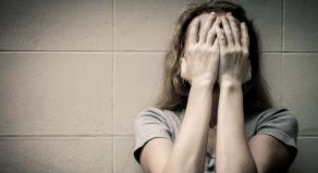 A woman holds her face in her hands