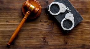 A photograph of a courtroom gavel and police handcuffs