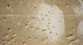 A stock photo showing bullet holes in a concrete wall