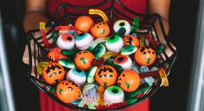 A woman holding a bowl of Halloween sweets