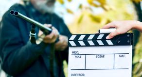 A stock image of a man with a gun and a movie set clapperboard