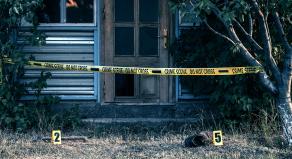 A stock image showing police tape outside of a house and a shoe on a front lawn