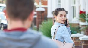 A woman looks over her shoulder as a man is following her