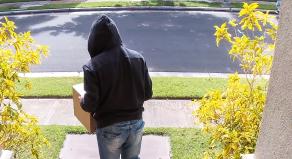 A thief stealing a parcel from a porch