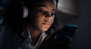 A woman listens to a podcast at night