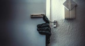 A leather-gloved hand reaching around a door