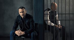 Will Mellor next to a policeman in a prison cell