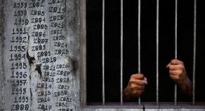 A prisoner behind bars with dates written on the prison walls