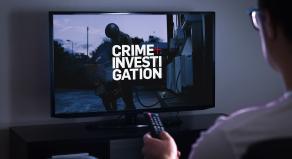 A person watching TV with Crime+Investigation on the screen