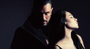 A man looks menacingly over a woman's shoulder at the camer