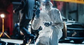 A photograph of a forensics specialist finding a bullet shell at a crime scene