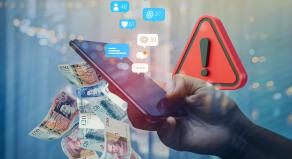 A person holding a mobile phone with a warning triangle, social media likes and UK banknotes