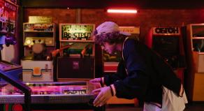 A young person playing pinball