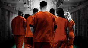 Prisoners wearing orange jumpsuits walking away from the camera