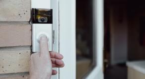 A person pressing a smart doorbell with their thumb