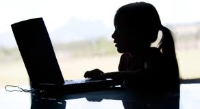 Silhouette of a young girl using a laptop computer