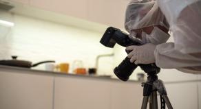 A crime scene photographer takes pictures in a kitchen