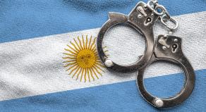 A pair of police handcuffs on top of the Argentina flag