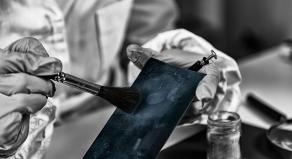 A forensic expert dusting for fingerprints in a lab