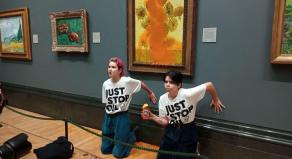 Phoebe Plummer and Anna Holland with their hands glued to the wall beneath Van Gogh's 'Sunflowers' which they have thrown tomato soup over