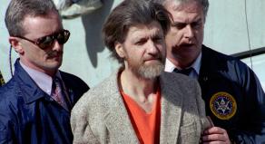Ted Kaczynski is flanked by federal agents as he is led to a car from a federal courthouse