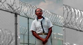 Wayne Williams poses along the fence line of a prison in a 1999 file photo