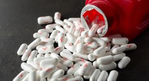A red Tylenol bottle with pills spilling out