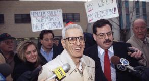 Dr Jack Kevorkian smiles as he arrives at police headquarters in 1993 surrounded by media and his supporters