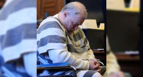 Richard Beasley sits in court in a wheelchair with his head slumped forwards