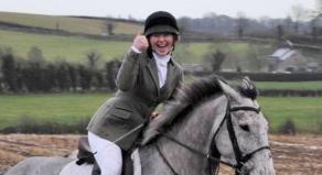 Katie Simpson gives a thumbs up while riding a horse