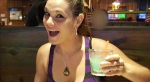 Monica Hoffa smiles while holding a drink in a bar
