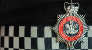 South Wales Police badge on a black and white checked background