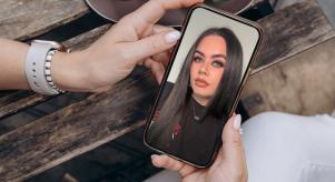 A woman holding a smartphone with an image of True Crime Caitlyn on