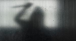 Silhouette of someone wielding a knife behind frosted glass