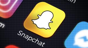 The Snapchat app on a phone screen next to other social media apps