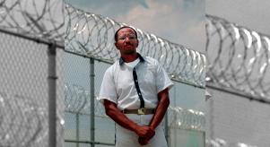 Wayne Williams poses along the fence line of a prison in a 1999 file photo